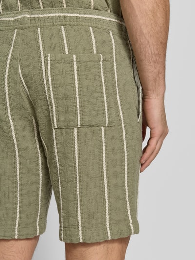 Männermodel trägt Shorts mit elastischem Bund und Tunnelzug von MCNEAL in Olive mit weißen Streifen, Reine Baumwolle, Nahaufnahme Rückansicht.