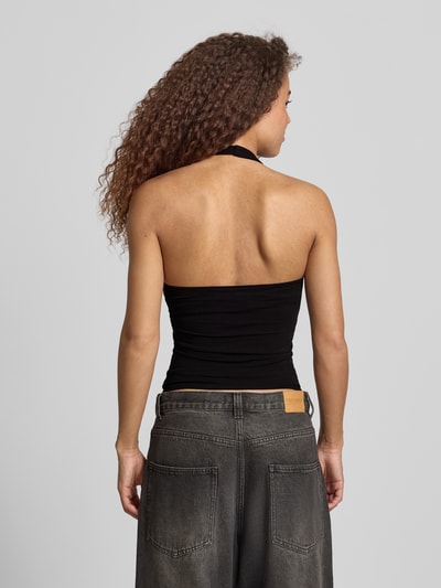 Frauenmodel trägt figurbetontes Neckholder-Top mit Rundhalsausschnitt von REVIEW im Baumwoll-Elasthan-Mix, Slim-Fit, Rückenlänge 32 cm, schwarze Farbe, glatte Textur, Ganzkörperansicht Rückansicht.