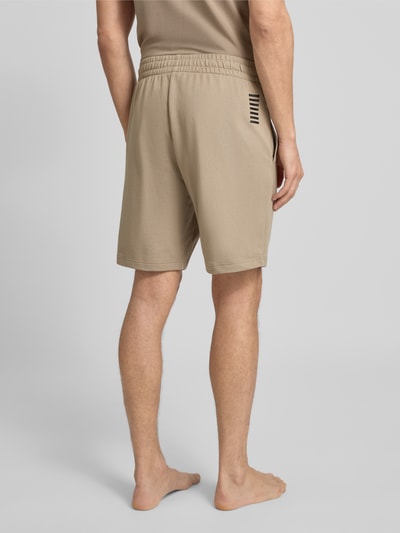 Mężczyzna model nosi Szorty z elastycznym pasem i logo od EA7 Emporio Armani, bawełna, krój regular fit, widok całej sylwetki z tyłu.