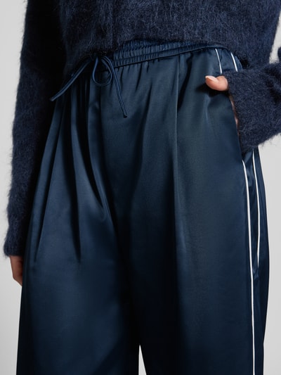 Vrouwenmodel draagt donkerblauwe Sweatpants met viscose van Gestuz, model 'BICCA', galonstrepen, elastische band met tunnelkoord, relaxed fit, detailopname taille.