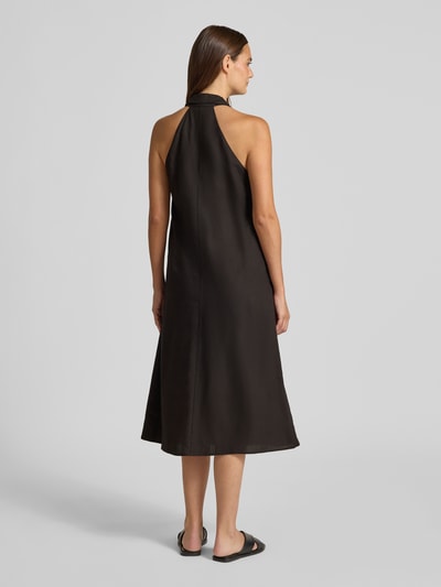 Frauenmodel trägt Midikleid aus Viskose-Mix mit Neckholder Modell 'Qudia' von Someday in Schwarz, Rückenansicht, Loose-Fit, glatte strukturierte Oberfläche, Damen Midikleid mit Leinen-Viskose-Anteil, Nahtreißverschluss, Rückenlänge 116 cm, Brustweite 48 cm, Ganzkörperansicht Rückansicht.