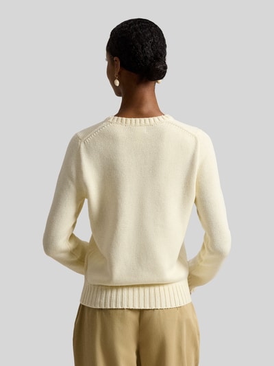 Frauenmodel trägt Strickpullover mit Flaggen-Motiv und Rundhalsausschnitt von Polo Ralph Lauren aus reiner Baumwolle, Rückenlänge 57 cm, Ärmellänge 63 cm, Regular Fit, cremefarben, feine Strickstruktur, Ganzkörperansicht Rückansicht.