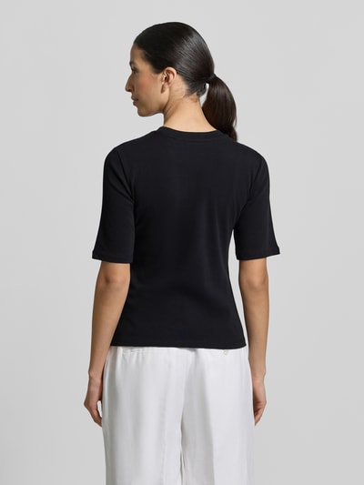 Frauenmodel trägt Slim Fit T-Shirt im Halbarm-Design von Christian Berg Woman aus elastischem Baumwoll-Mix in Schwarz, Rückenlänge 54 cm, Ganzkörperansicht Rückansicht.