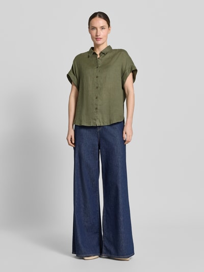 Frauenmodel trägt Leinenbluse mit Knopfleiste Modell 'DOLLY' von 0039 Italy in Olive, Regular-Fit, Hemdblusenkragen, kurze Ärmel mit Aufschlag, Rückenlänge 64 cm bei Größe S, Ganzkörperansicht von vorne.