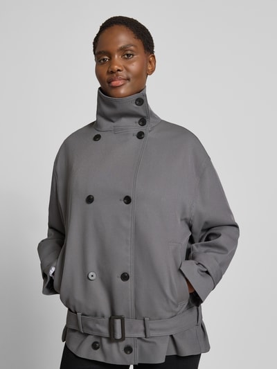 Frauenmodel trägt Jacke mit Stehkragen Modell 'DARIO' von MANGO in Grau, Material-Mix, Doppelknopfleiste, Gürtel, Nahaufnahme Oberkörper.