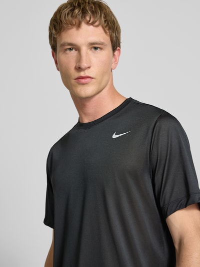 Mężczyznamodel nosi T-Shirt mit Logo-Print und Rundhalsausschnitt von NIKE TRAINING, czarny kolor, prosty krój, z nadrukiem logo, nahaufnahme górnej części ciała.
