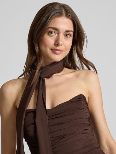 Frauenmodel trägt Cocktailkleid im Off-Shoulder-Look Modell 'Arli' von Forever New, Material-Mix mit Stretch-Anteil, Drapierungen, Knotendetail, figurbetonter Schnitt, Maxikleid, braun, Nahaufnahme Oberkörper.