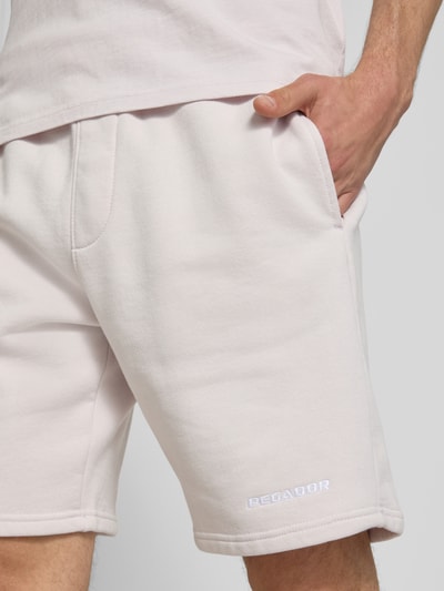 Männermodel trägt Regular Fit Shorts mit Logo-Stitching von Pegador aus Baumwoll-Mix, helle Farbe, Nahaufnahme Oberschenkel.