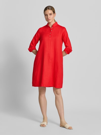 Vrouwenmodel draagt Leinenkleid mit Stehkragen und kurzer Knopfleiste van Christian Berg Woman, rood linnen, rechte fit, knielengte, korte staande kraag, korte knopenlijst, mouwen met vaste omslag, vooraanzicht volledige lichaamsopname.