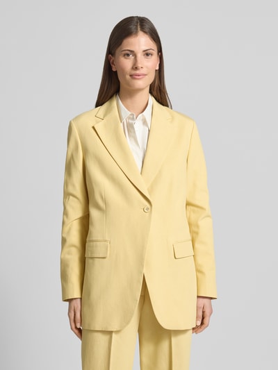 Vrouwenmodel draagt Relaxed Fit Blazer met Pattentaschen van Scotch & Soda in lichtgeel, mix van katoen en lyocell, reverskraag, knoopsluiting, klepzakken, ruglengte maat S 74 cm, borstwijdte maat S 42 cm, mouwlengte maat S 62 cm, full body vooraanzicht.