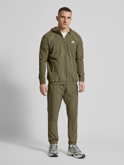Männermodel trägt Regular Fit Sweatpants mit elastischem Bund mit Logo-Print Modell 'TECH APP S-PANT' von adidas Training, Optik: Unifarben, Passform: Regular-Fit, Label-Print, Logo-Detail, Kontrast-Nähte, seitliche Eingrifftaschen, Materialverarbeitung: Batist, Ganzkörperansicht von vorne.
