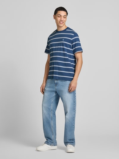 Männermodel trägt T-Shirt mit Logo-Stitching von Calvin Klein Jeans aus Reine Baumwolle, Gerader-Schnitt, Rundhalsausschnitt, Rückenlänge bei Größe M 69 cm, Ganzkörperansicht von vorne.