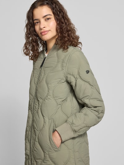 Frauenmodel trägt Steppjacke mit Stehkragen und Eingrifftaschen von Superdry in Olivgrün, strukturierte Oberfläche, Ganzkörperansicht von vorne; Regular Fit, Reißverschluss, Rückenlänge 91 cm, Schulterbreite 38 cm, Brustweite 50 cm, Ärmellänge 63 cm.