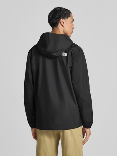 Männermodel trägt Jacke mit Label-Print Modell 'ANTORA' von The North Face in Schwarz mit Kapuze und elastischen Ärmelabschlüssen, Ganzkörperansicht Rückansicht. Kontext: Herren Jacke, gerade Passform, Kapuze mit Tunnelzug, Reißverschlusstaschen, durchgehender Reißverschluss mit Abdeckleiste, Rückenlänge 74 cm, Schulterbreite 47 cm, Brustweite 58 cm, Ärmellänge 68 cm.
