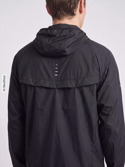 Männermodel trägt schwarze Regular Fit Trainingsjacke aus reiner Baumwolle Modell 'STRIDE' von Nike Training, Ganzkörperansicht Rückansicht, KI-modifiziertes Bild.