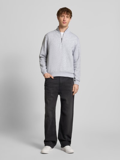 Männermodel trägt Regular Fit Sweatshirt mit Troyer-Kragen Modell 'Bradley' von JACK & JONES in Hellgrau, Material-Mix, elastische Abschlüsse, Ganzkörperansicht von vorne.