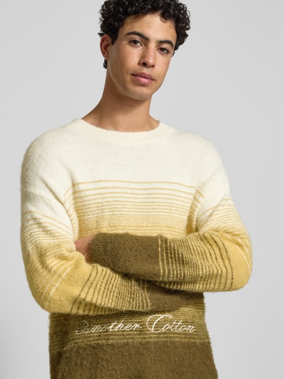 Männermodel trägt Oversized Strickpullover mit gerippten Abschlüssen von ANOTHER COTTON LAB, gestreift, Baumwoll-Mix, Nahaufnahme Oberkörper.