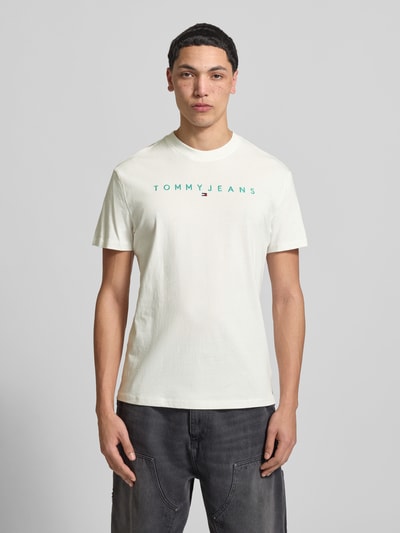 Männermodel trägt Regular Fit T-Shirt aus reiner Baumwolle von Tommy Jeans, weiß, unifarben, Rundhals, Label- und Logo-Stitching, Ganzkörperansicht von vorne.