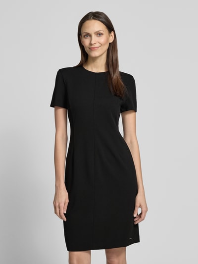 Modelka kobieca ma na sobie Knielanges Etuikleid mit Rundhalsausschnitt von Calvin Klein Womenswear, czarny materiał z domieszką stretchu, prosty krój, długość do kolan, okrągły dekolt, długość tyłu w rozmiarze S: 92 cm, szerokość w rozmiarze S: 43 cm, długość rękawa w rozmiarze S: 19 cm, pełen widok z przodu