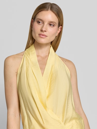 Frauenmodel trägt Regular Fit Top aus Viskose-Mix Modell 'Salma' von GUIDO MARIA KRETSCHMER WOMAN, Wickel-Optik, Neckholder, V-Ausschnitt, Raffungen, ärmelloses Design, cremegelb mit feiner Struktur, Nahaufnahme Oberkörper.