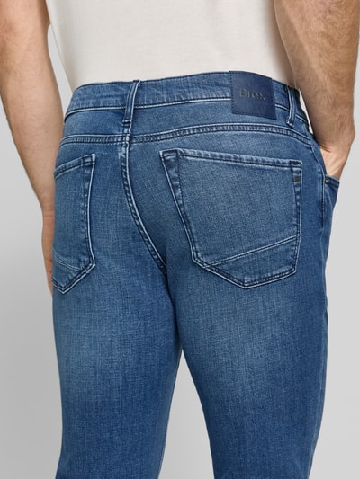 Männermodel trägt Modern Fit Jeans aus katoenmix Model 'Chuck' van Brax in denimlook met labelpatch, labeldetail, riemlussen, knoop- en ritssluiting, 5-pocketmodel, twill materiaalverwerking. Detailopname achterzijde.