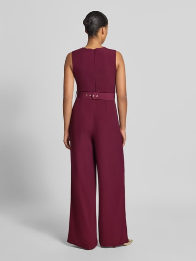 Frauenmodel trägt Jumpsuit mit Stoffgürtel von Rinascimento in Bordeaux mit weitem Bein und Rückseitendetails, Ganzkörperansicht Rückansicht. Material-Mix mit Stretch-Anteil, taillierte Passform, ärmellos, Raffungen, Rückseitiger Reißverschluss, Rückenlänge 36 cm, Brustweite 38 cm, Gesamtlänge 149 cm, Innenbeinlänge 80 cm.