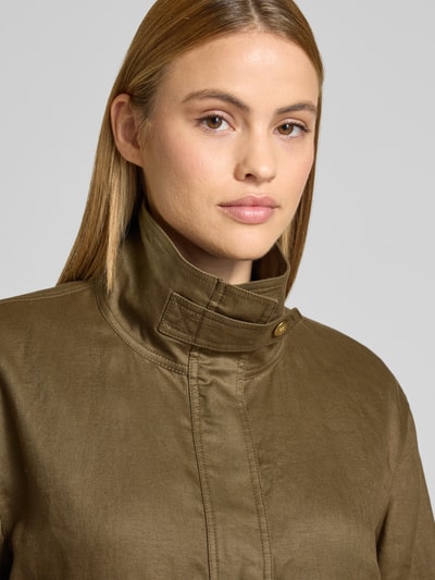 Frauenmodel trägt Relaxed Fit Utility-Jacke aus reinem Leinen von Tommy Hilfiger in Oliv, Metall-Logo, verdeckte Knopfleiste, Nahaufnahme Oberkörper.