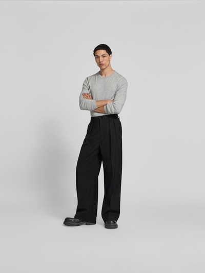 Männermodel trägt Wide Fit Stoffhose aus Woll-Mix von Filippa K in Schwarz mit Kellerfalten und Gesäßtaschen, Ganzkörperansicht von vorne.