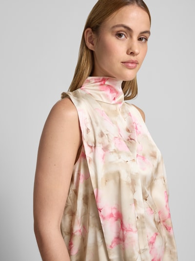 Kobieta nosi Bluse mit Stehkragen und asymmetrischem Design od Rinascimento, materiał z domieszką stretchu, prosty krój, marszczenia, jasnoróżowe i beżowe odcienie, lekko błyszcząca tekstura, kluczowy dekolt z tyłu, ujęcie z przodu, zbliżenie górnej części ciała.