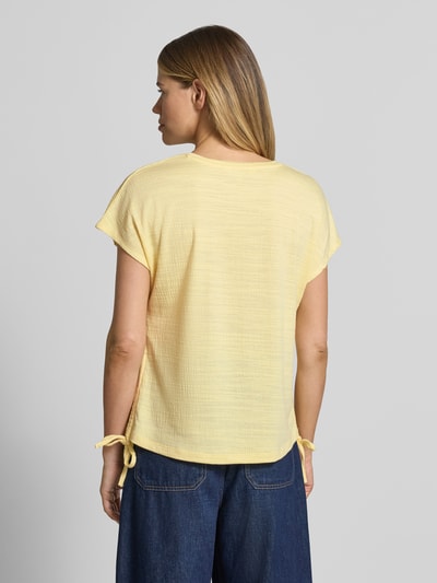 Frauenmodel trägt Regular Fit T-Shirt mit Viskose-Anteil von Apricot, gelb, Strukturmuster, Zierschleifen, Rückenansicht, Ganzkörperansicht Rückansicht.