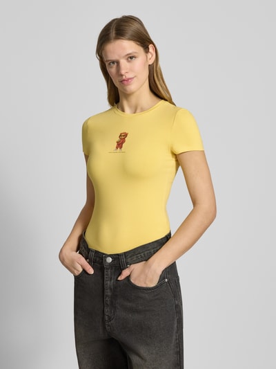Frauenmodel trägt Slim Fit T-Shirt mit Logo-Print Modell 'Sweet' von Review aus elastischem Baumwoll-Mix in Gelb, Nahaufnahme Oberkörper