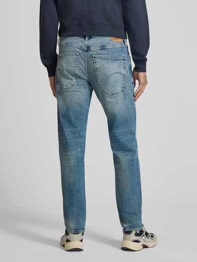 Männermodel trägt Slim Fit Jeans aus Baumwoll-Mix Modell 'Streem' von G-Star RAW in mittlerem Blau, dezente Waschung, Ganzkörperansicht Rückansicht.