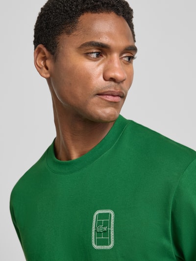 Männermodel trägt Regular Fit T-Shirt aus reiner Baumwolle Modell 'CN Tenniscourt Backprint' von Lacoste in sattem Grün, Nahaufnahme Oberkörper, Herren T-Shirt.