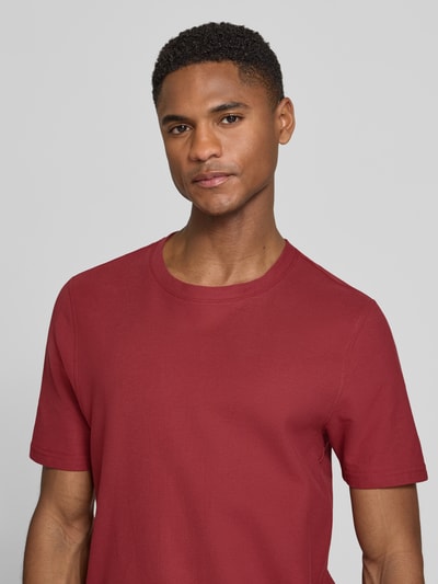 Männermodel trägt T-Shirt mit Rundhalsausschnitt von MCNEAL in Rot, reine Baumwolle, Slim Fit, glatte Oberfläche, Nahaufnahme Oberkörper.