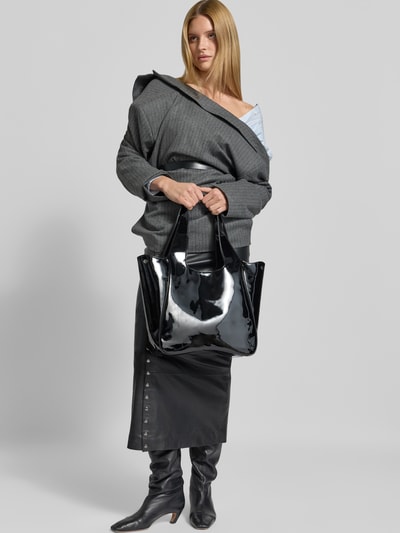 Frauenmodel trägt glänzenden Shopper mit Logo-Detail von Diesel, Schwarz, Magnetverschluss, Schulterriemen, Ganzkörperansicht von vorne.
