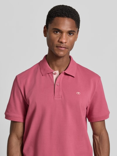 Männermodel trägt Regular Fit Poloshirt aus reiner Baumwolle von Tom Tailor in Rosa, glatte Textur, Nahaufnahme Oberkörper. Herren Poloshirt.