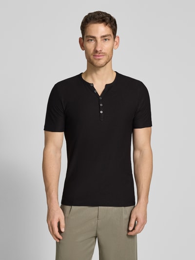 Männermodel trägt T-Shirt mit V-Ausschnitt und Knopfleiste von MCNEAL in Schwarz, Reine Baumwolle, Regular-Fit, Ganzkörperansicht von vorne.