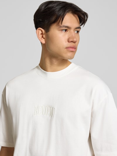 Męski model nosi T-Shirt mit Label-Stitching und Rundhalsausschnitt od REVIEW, bawełna, krój relaxed fit, detal haftu, zbliżenie na górę ciała