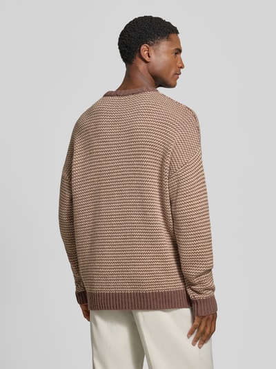 Männermodel trägt Relaxed Fit Strickpullover mit Streifen-Muster Modell 'NEELIO' von DRYKORN, beige-braun, Struktur-Strick, Ganzkörperansicht Rückansicht. Material-Mix mit Woll-Anteil, elastische Abschlüsse, Rückenlänge 70 cm, Ärmellänge 56 cm.