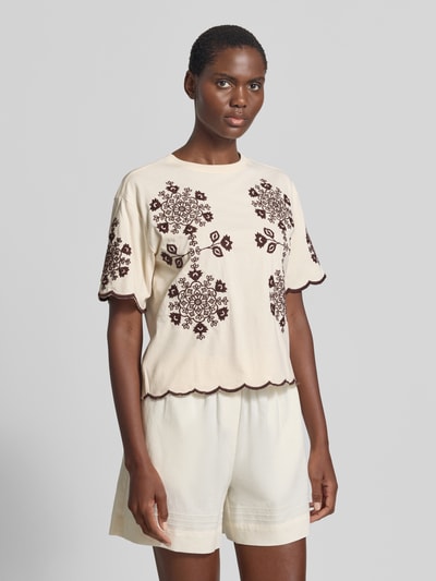 Vrouwenmodel draagt T-Shirt met Wellensaum und Motiv-Stitching van Jake*s Casual in crème met bruin motief, rechte fit, pure katoen, ronde hals, lengte 50 cm, geheel lichaamsaanzicht schuin van voren.