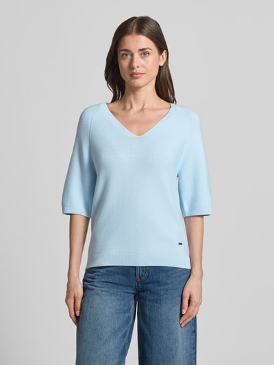 Frauenmodel trägt Regular Fit Strickpullover aus Baumwoll-Mix von s.Oliver RED LABEL, Optik: Unifarben, Logo-Applikation aus Metall, V-Ausschnitt, Kurzarm, Raglanärmel, Ärmelabschluss und Rumpfabschluss gerippt, Materialverarbeitung: Strick, Material: Baumwoll-Mix, Hellblau, glatte Textur, Ganzkörperansicht von vorne.