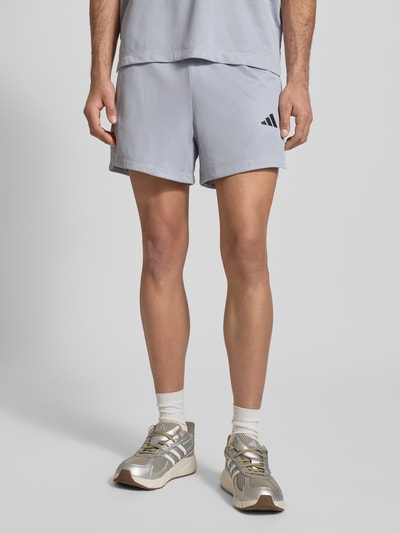 Männermodel trägt Shorts mit Label-Print von adidas Training, hellgrau, Lockerer-Schnitt, Elastischer-Bund, Ganzkörperansicht von vorne.