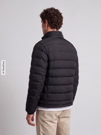 Männermodel trägt schwarze Regular Fit Steppjacke mit Stehkragen Modell 'MODENA FUSED' von Strellson, Herren Steppjacke, Ganzkörperansicht Rückansicht, KI-modifiziertes Bild.