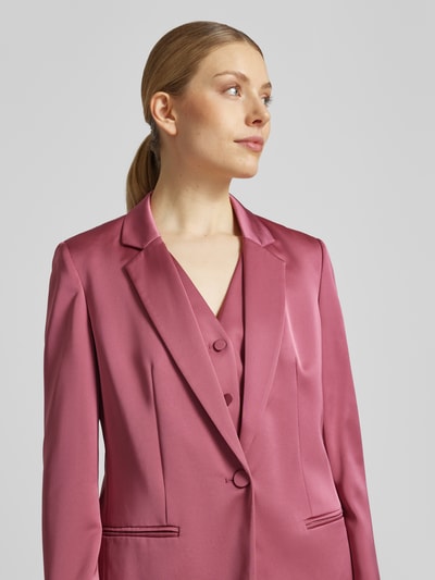 Frauenmodel trägt Slim Fit Blazer mit Paspeltaschen von Jake*s Cocktail aus Satin in Rosa mit Reverskragen, Knopfverschluss, Nahaufnahme Oberkörper.
