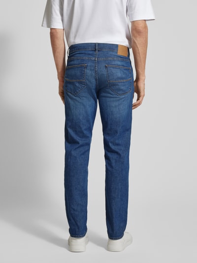 Männermodel trägt Sraight Fit Jeans mit Eingrifftaschen Modell 'Cadiz' von Brax, Blau im Used-Look, Ganzkörperansicht Rückansicht. Baumwoll-Elasthan-Mix, Bundweite 45 cm, Innenbeinlänge 81 cm bei Größe 32/32.