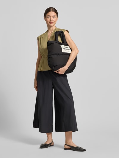 Frauenmodel trägt Handtasche mit Label-Detail und Steppnähten von MADS NØRGAARD, schwarz, Tragehenkel, Schulterriemen, Maße 42x32x15 cm, Länge Schulterriemen 66 cm, Ganzkörperansicht von vorne.
