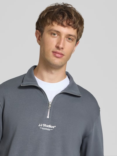 Männermodel trägt Regular Fit Sweatshirt aus Baumwoll-Mix Modell 'Soho' von JACK & JONES in Grau mit Logo-Print, Nahaufnahme Oberkörper.