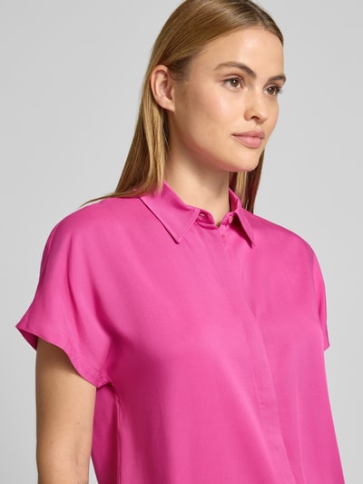 Frauenmodel trägt Relaxed Fit Hemdbluse aus reiner Viskose Modell 'LARISAANA' von Armedangels, Optik: Unifarben, Kragenform: Hemdkragen, V-Ausschnitt, Verschluss: einreihige Knopfleiste, Ärmelform: Kurzarm, Materialverarbeitung: Popeline, Material: reine Viskose, leuchtendes Pink, glatte Textur, Nahaufnahme Oberkörper.