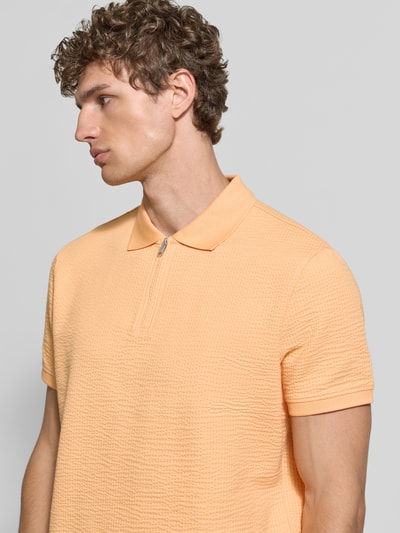 Männermodel trägt Regular Fit Poloshirt mit structuurpatroon van MCNEAL in perzikkleur, katoenmix, ritssluiting, met korte mouwen, ruglengte maat M 70 cm, Nahaufnahme Oberkörper.