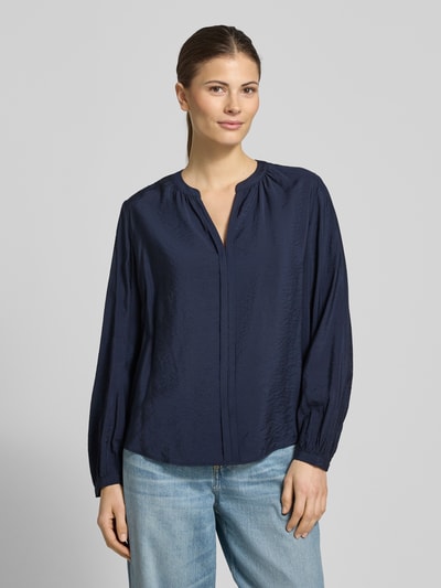 Vrouwenmodel draagt Relaxed Fit Langarmbluse aus Viskose-Mix van s.Oliver RED LABEL in donkerblauw, tuniekhals, afgeronde rompzoom, viscosemix. Ganzkörperansicht van voren.